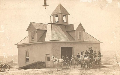 old fire house with horse-drawn fire carriages out front 