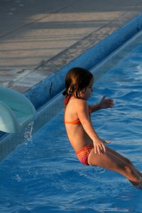 child sliding down a slide into the pool