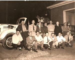 old group photo of fire department members standing in front of a truck